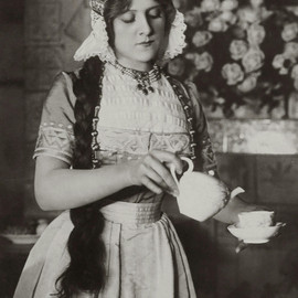 Frau aus dem frühen 20. Jahrhundert schenkt Kaffee ein.